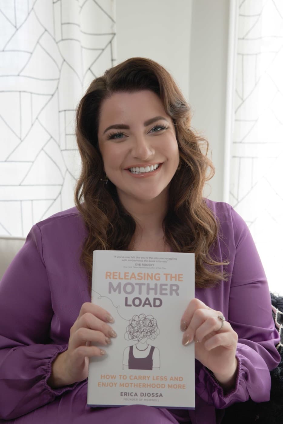 Erica Djossa holding her book, Releasing the Mother Load