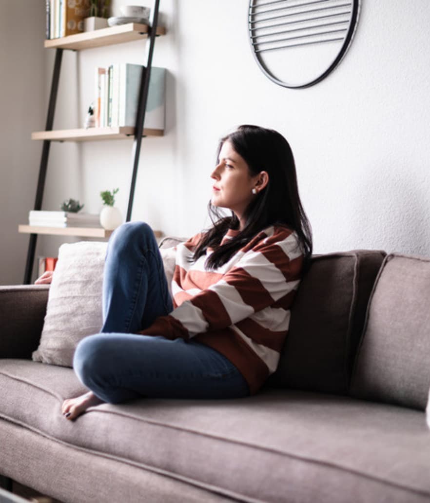 A woman on her couch, lost in thought