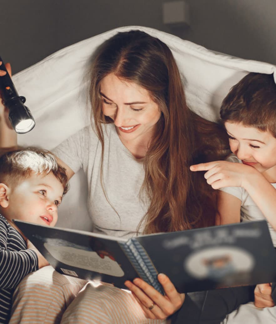 A mom reading with her kids under a blanket fort