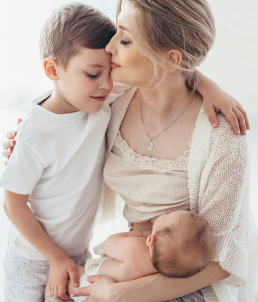 A mom holding her baby while her son leans in close
