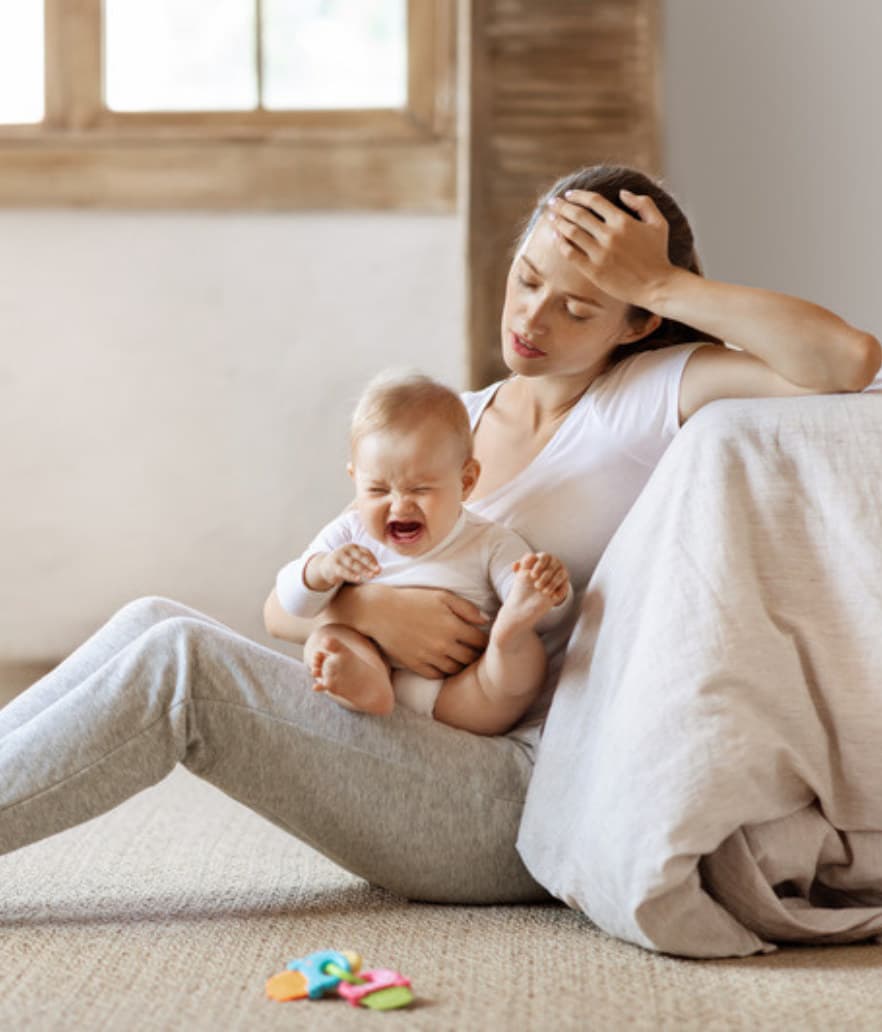 An exhausted mom holding her giggling baby