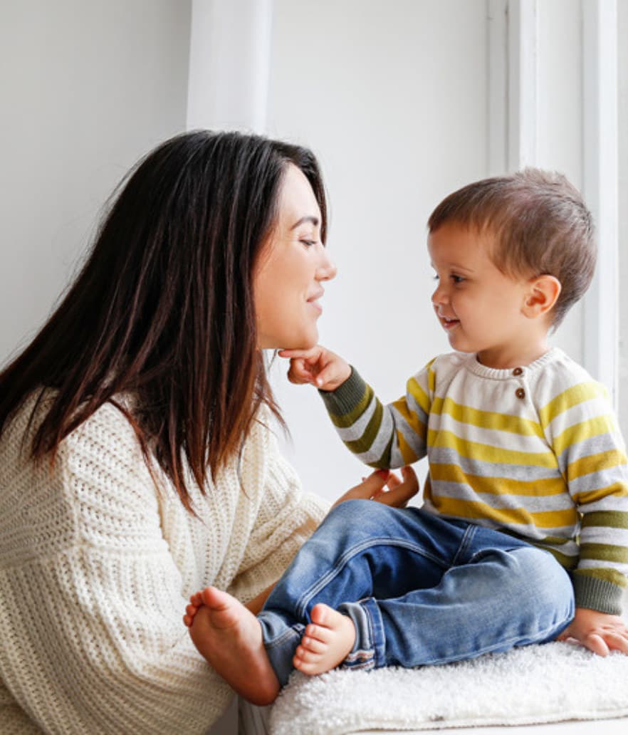 A mom talking calmly with her toddler on the couch