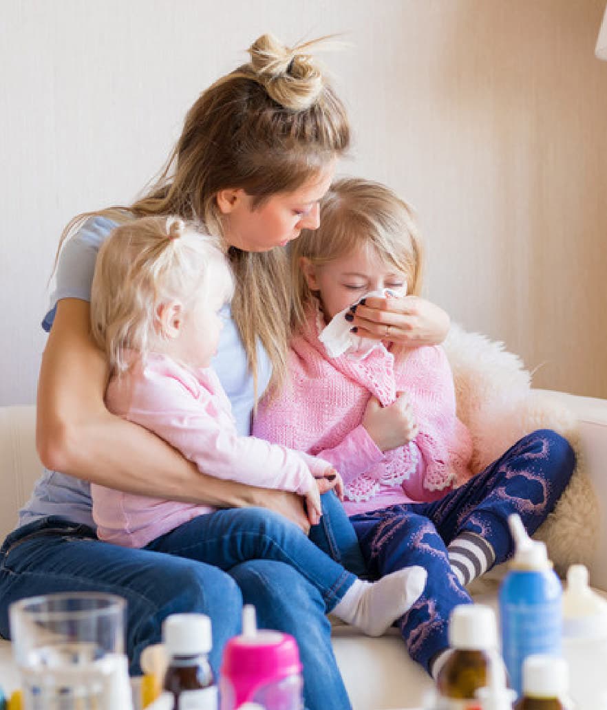 A mom caring for two sick kids on her lap
