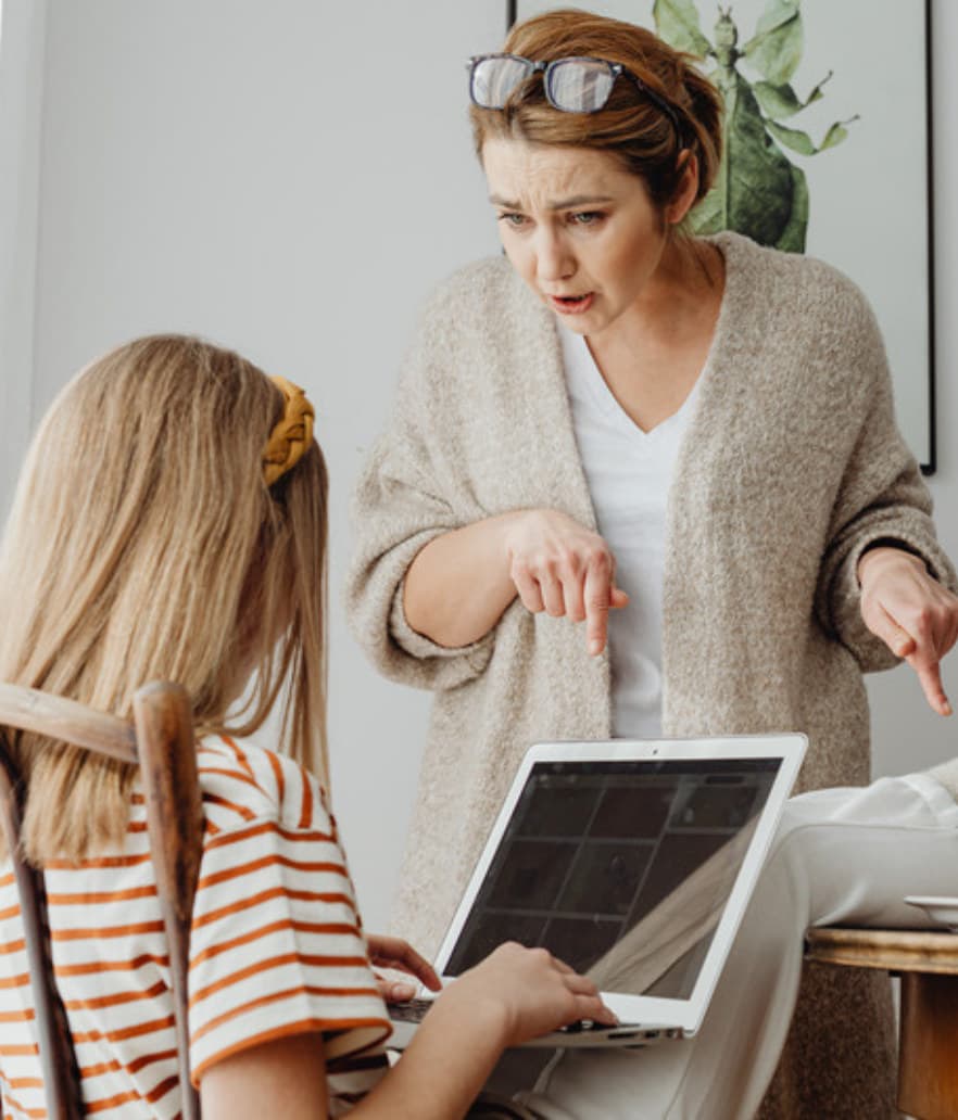 A stepmom and her stepdaughter looking at a laptop together