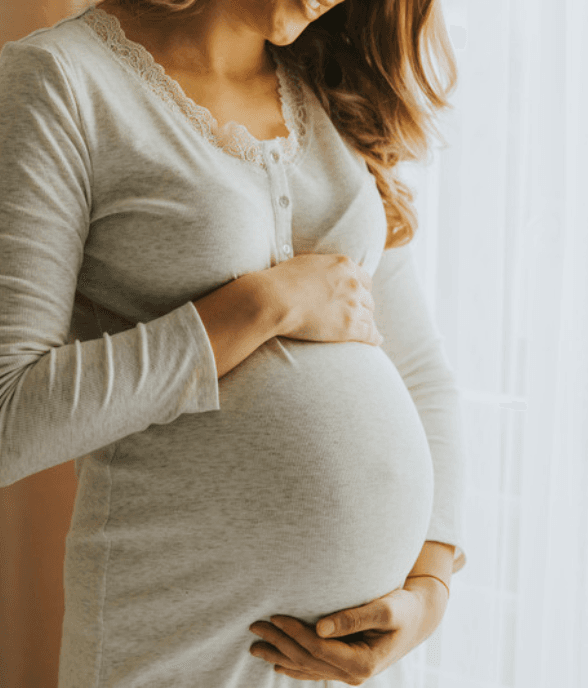 A pregnant mom with a hand on her belly, taking a breath