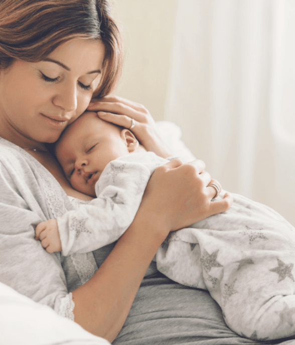 A mom cradling her sleeping newborn