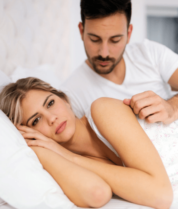 A mom lying awake in thought while her partner rests beside her