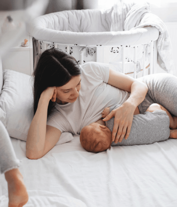 A mom resting on the bed with her baby