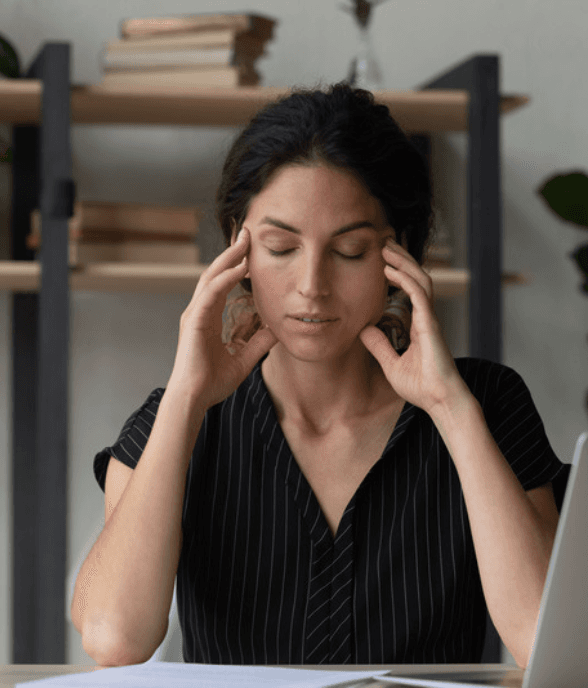 A mom pausing with her eyes closed, resting her temples