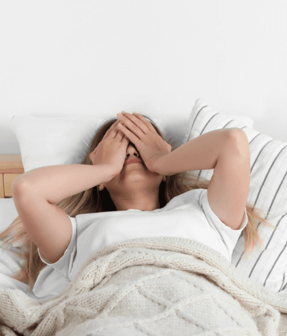A mom lying down with her hands over her face, depleted