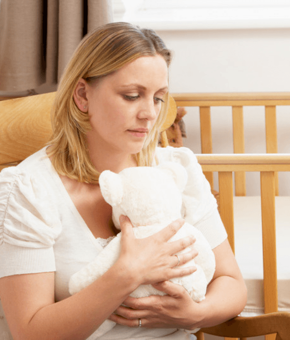 A mom standing quietly beside the crib
