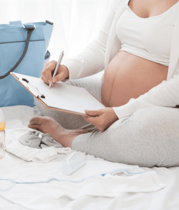 A pregnant mom writing in a notebook, thinking ahead