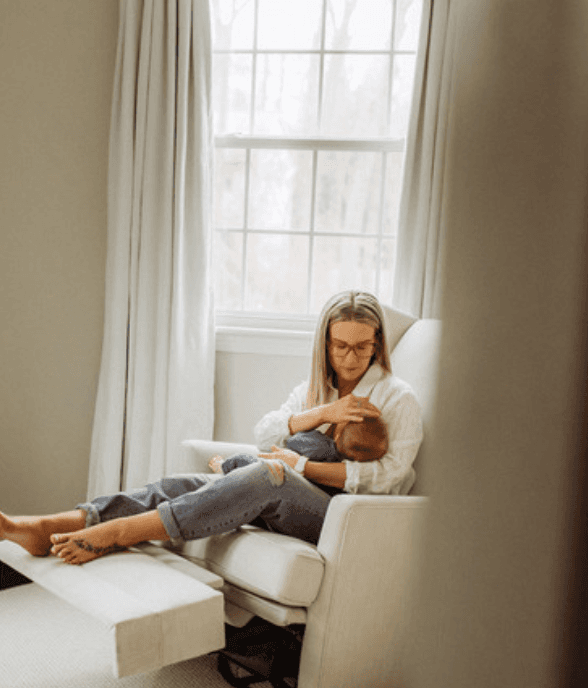 A weary mom sitting up holding her baby