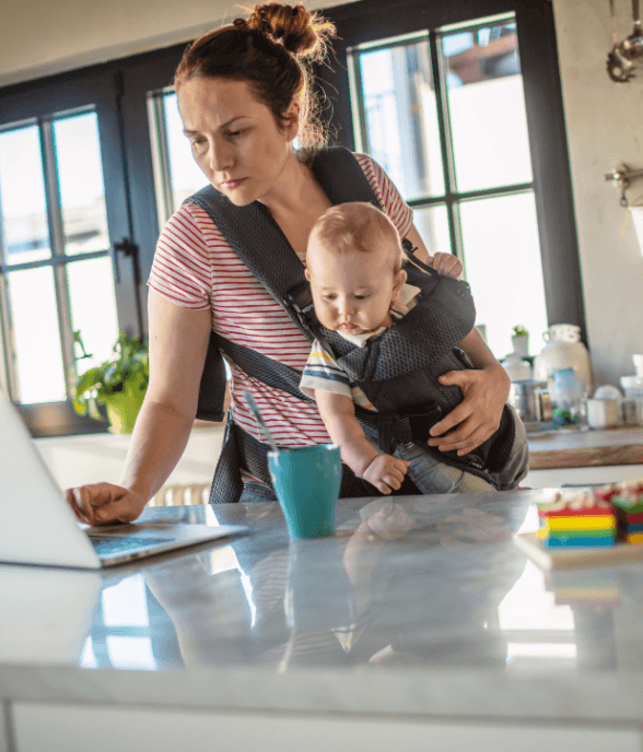 A mom managing tasks at the table with her child nearby
