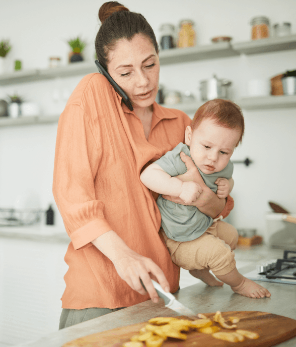 A mom multitasking in the kitchen while holding her child