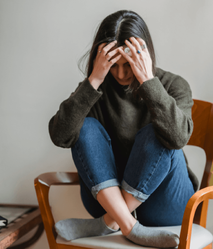 A woman sitting in a chair holding her head