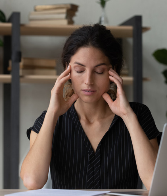 A mom pausing with her eyes closed, resting her temples